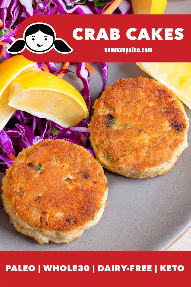 Two golden brown paleo crab cakes are on a beige plate, next to purple cabbage slaw and lemon wedges.